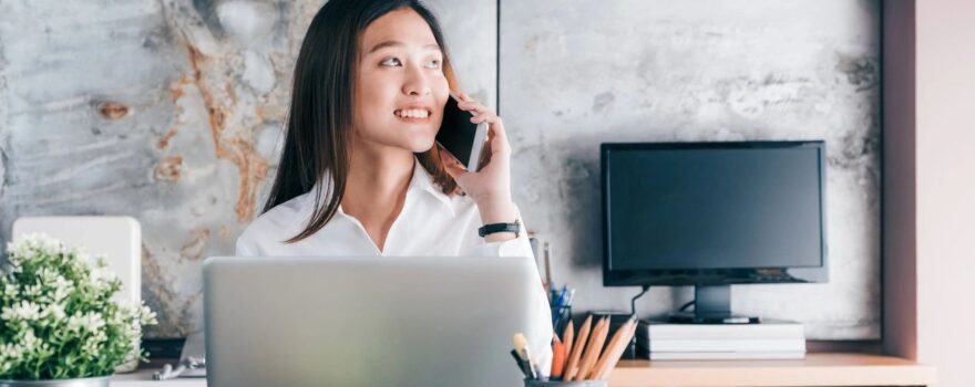 A woman sitting at her desk talking on the phone.